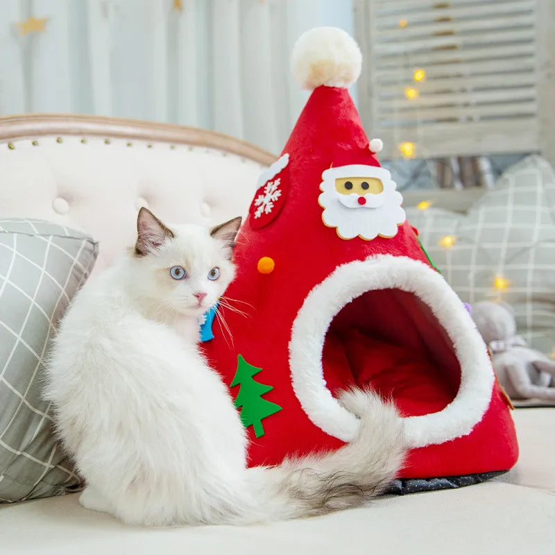 White cat sitting beside the red Christmas tree cave bed on a cream sofa
