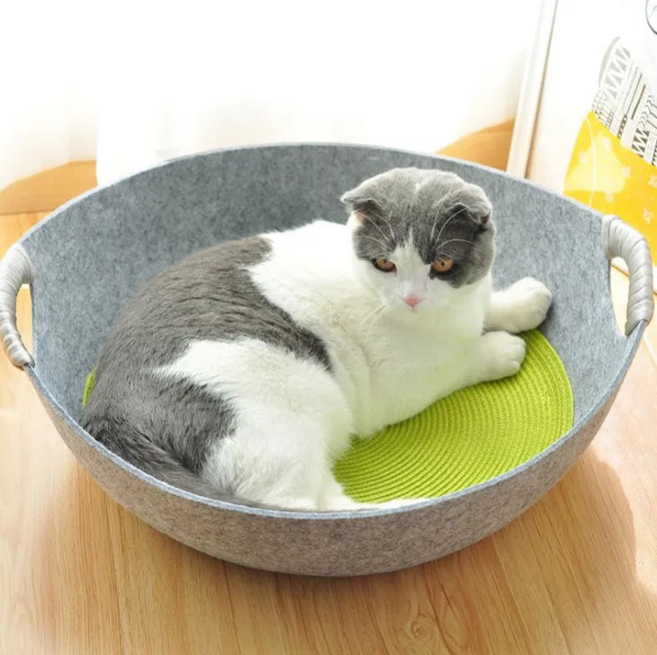 Grey and white cat lying in the light grey felt cat bed basket on a green woven mat