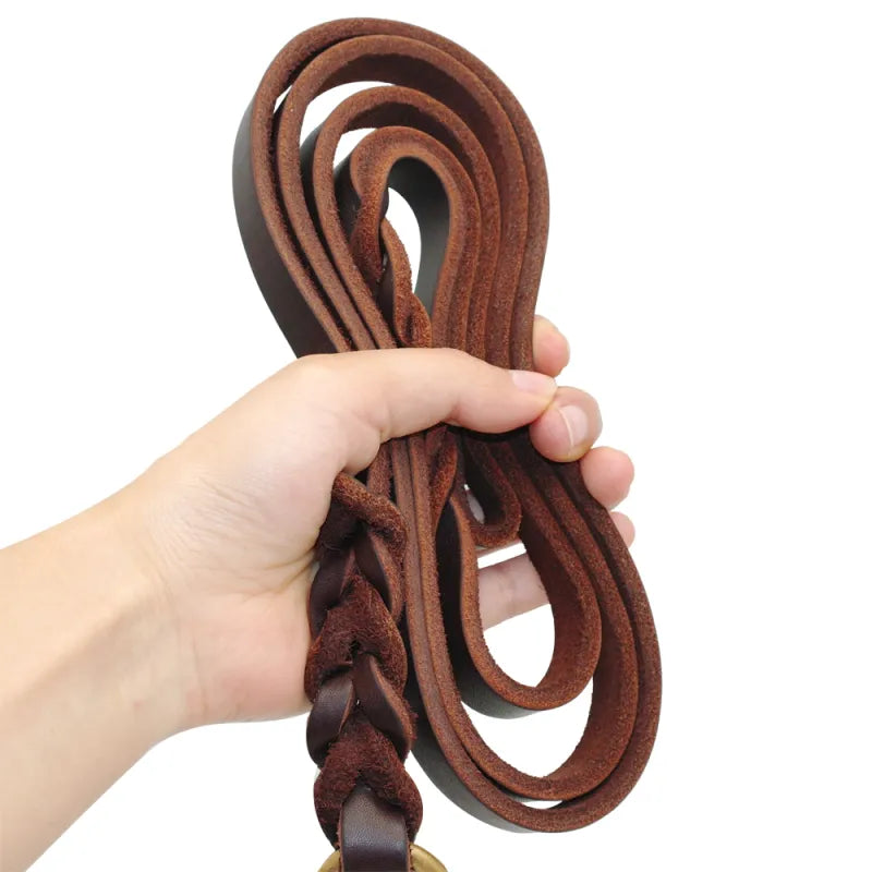 A hand holding the brown braided leather lead in coils