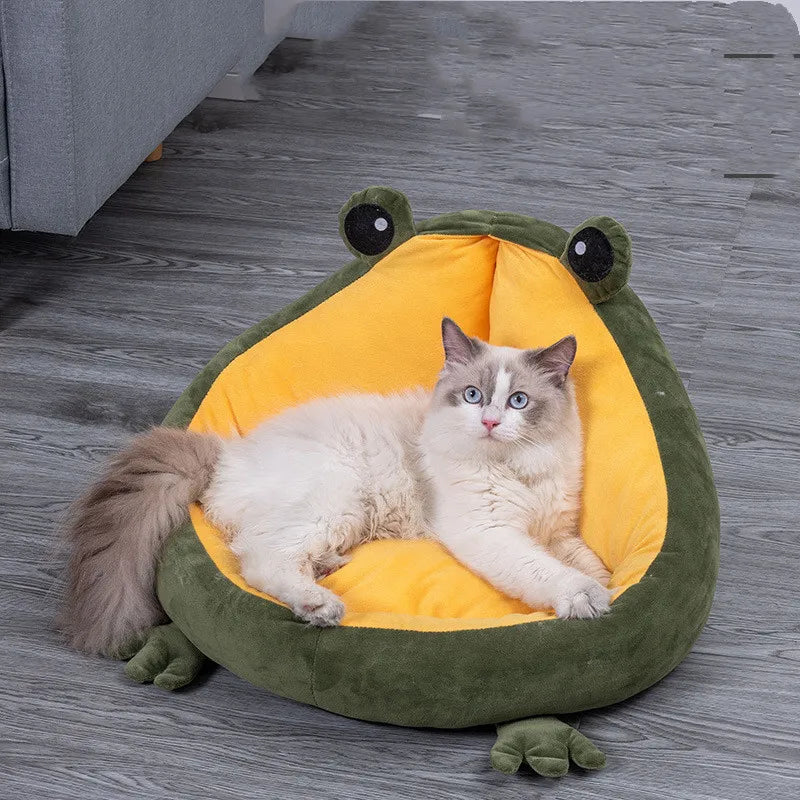 A long-haired cat lounging in the green frog-shaped bed with its yellow plush lining
