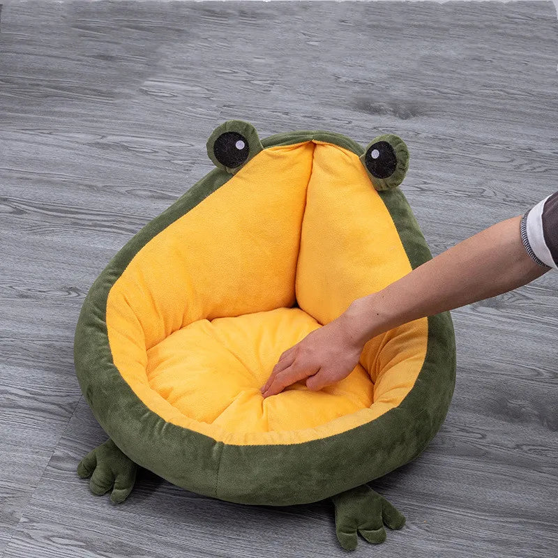 A hand pressing into the thick yellow cushion of the frog-shaped bed