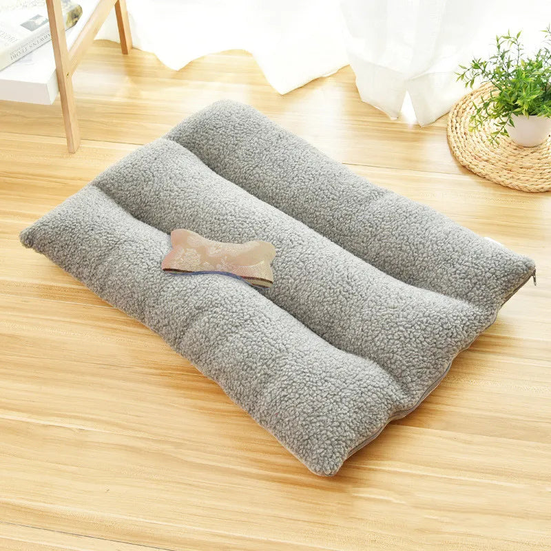 Grey curly-fleece dog cushion with three padded rolls on a wooden floor, a bone-shaped cushion on top