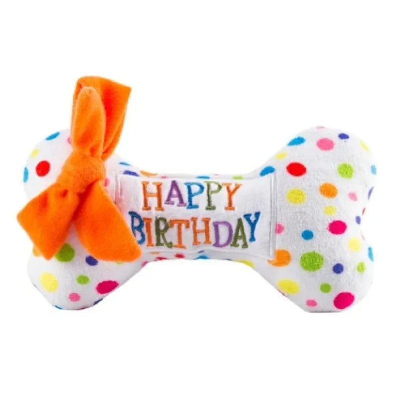 White polka-dot plush bone dog toy with an orange bow and stitched birthday lettering