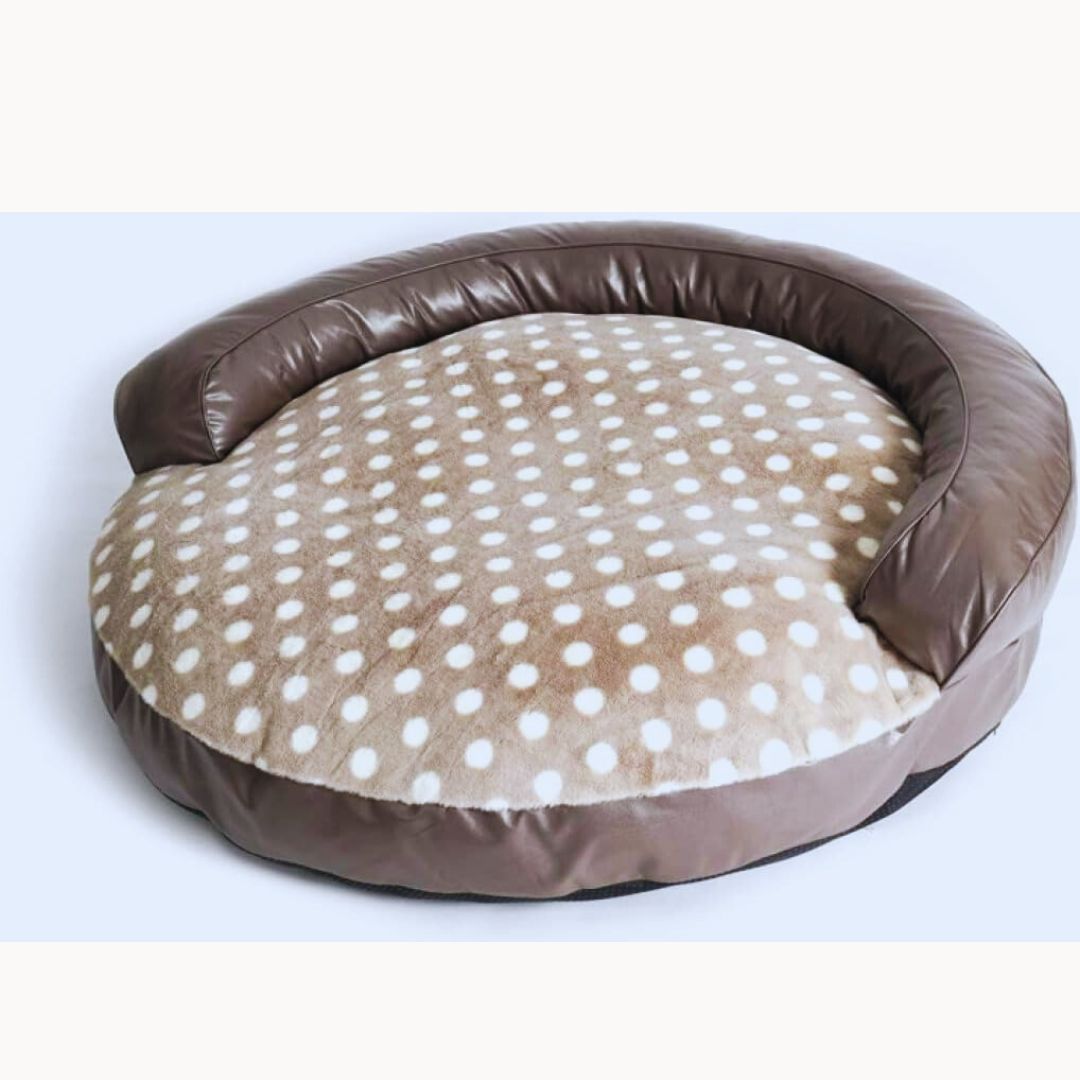 Round dog bed with a taupe leather-look bolster and a beige seat with white dots