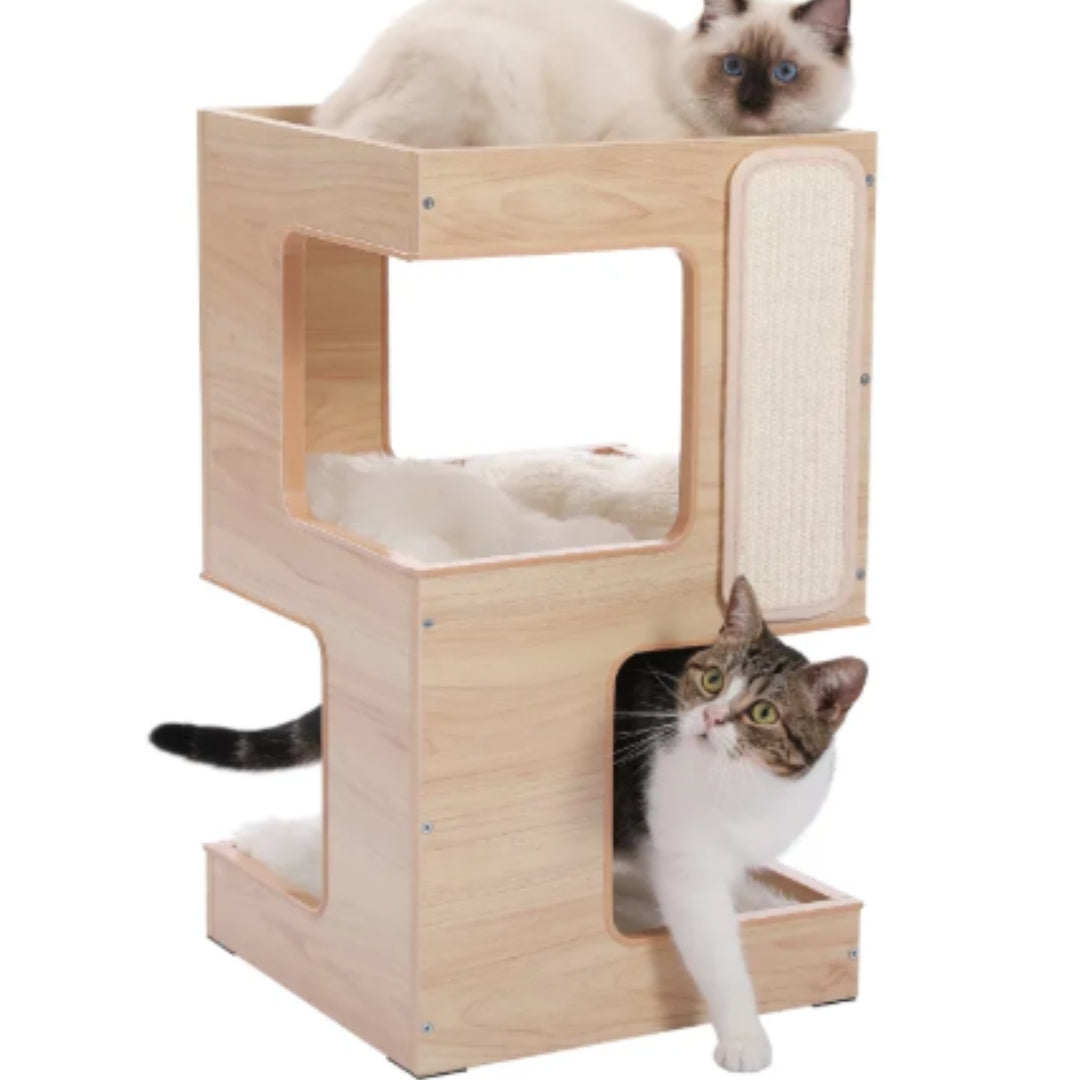 Two-tier wooden cat house on white with a cat on the top tray and a tabby cat stepping out of the cave