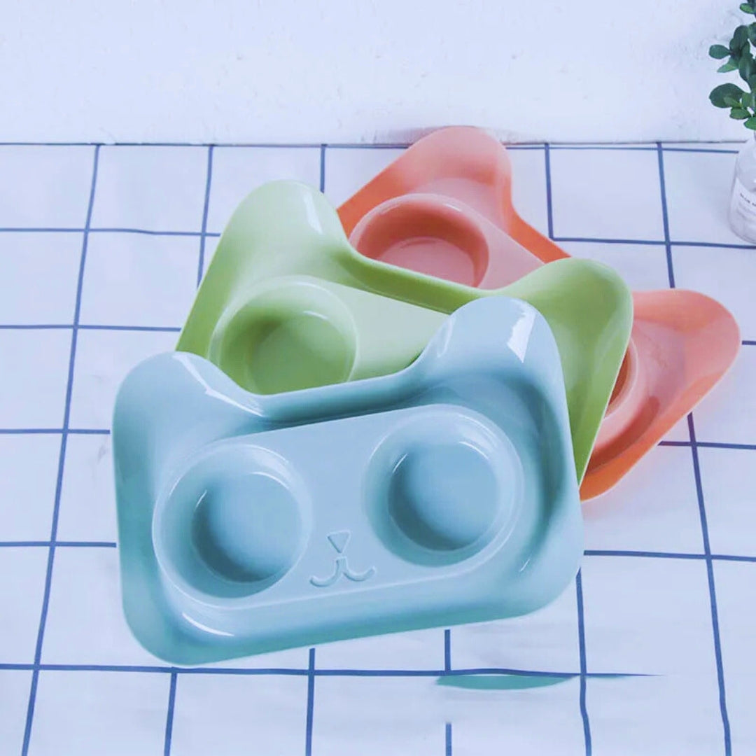 Three empty cat-shaped trays in mint, light green and peach, showing the recesses for the bowls