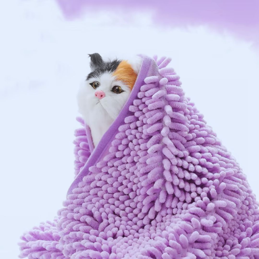 A white, black and ginger cat wrapped in a lilac chenille pet towel