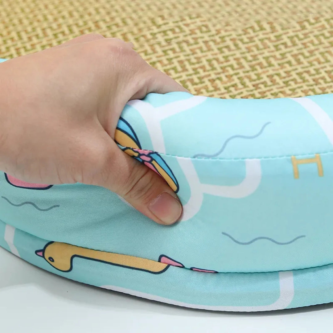 A hand squeezing the soft padded rim of the aqua duck print cat bed