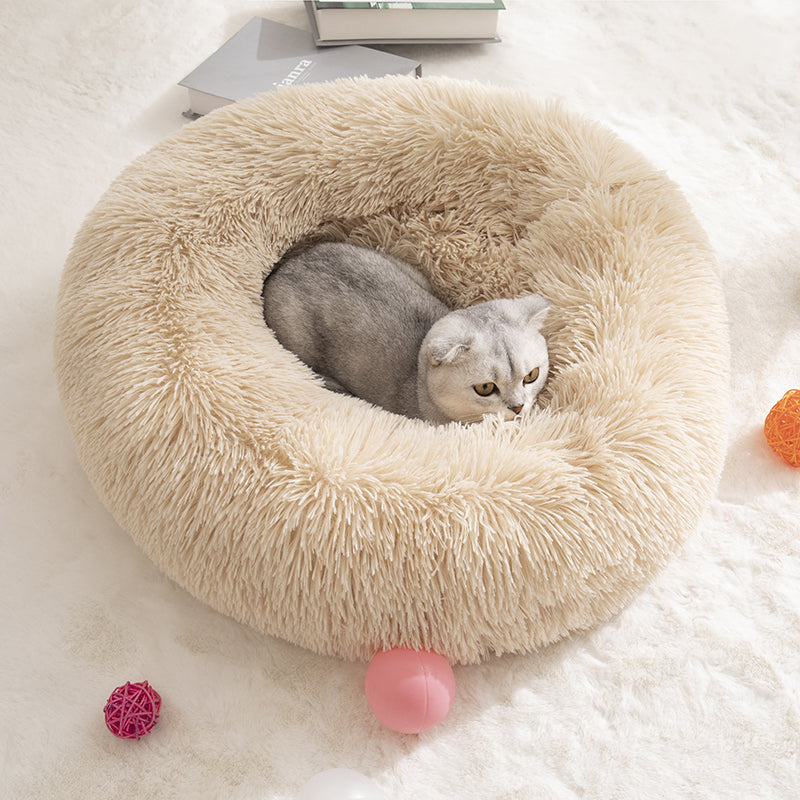 A cat curled up in a beige fluffy donut bed, a colour not offered