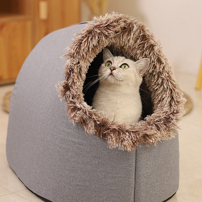 A cat sitting inside the grey cave bed, framed by its brown-tipped plush entrance