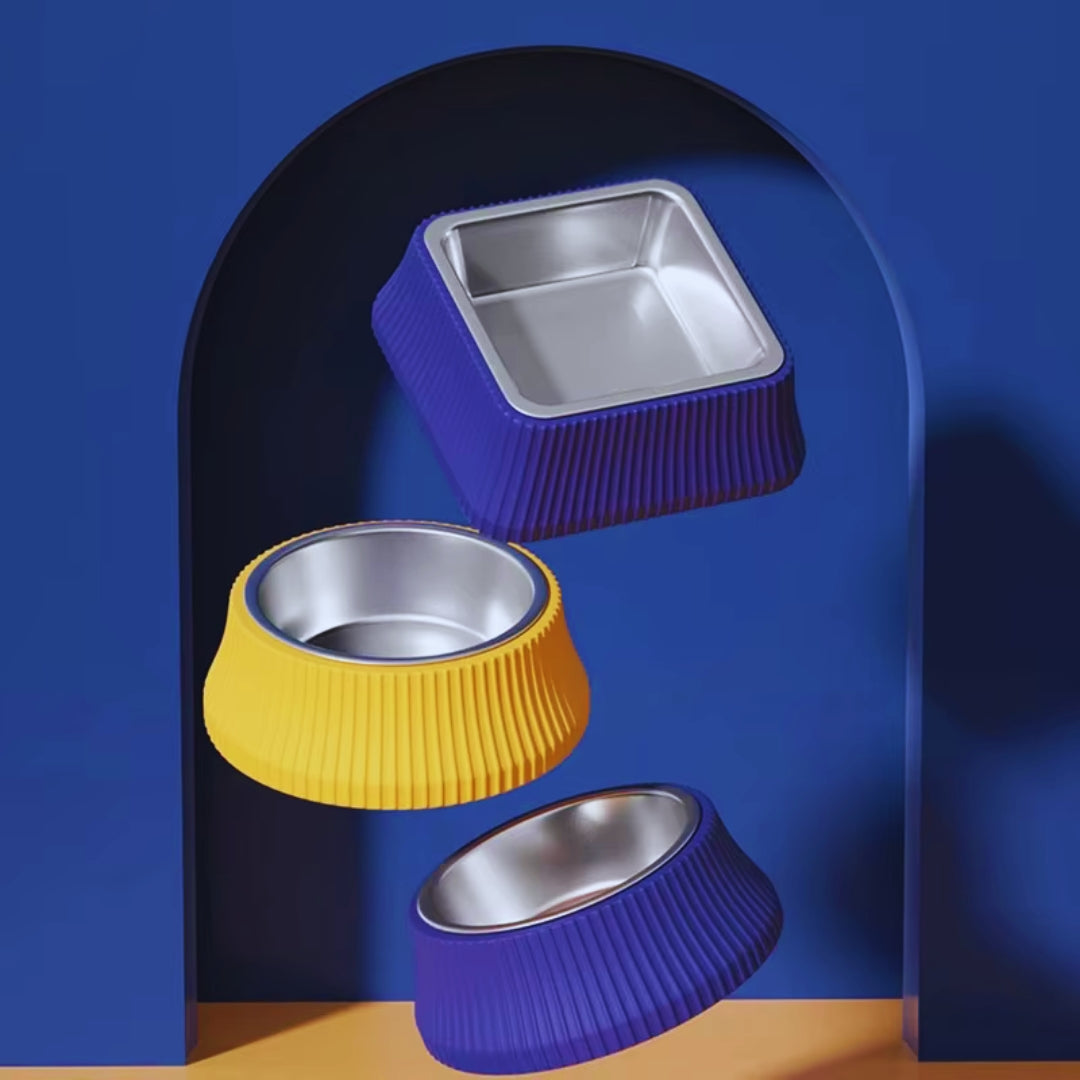 Three ribbed dog bowls in blue and yellow with steel inserts against a blue arch