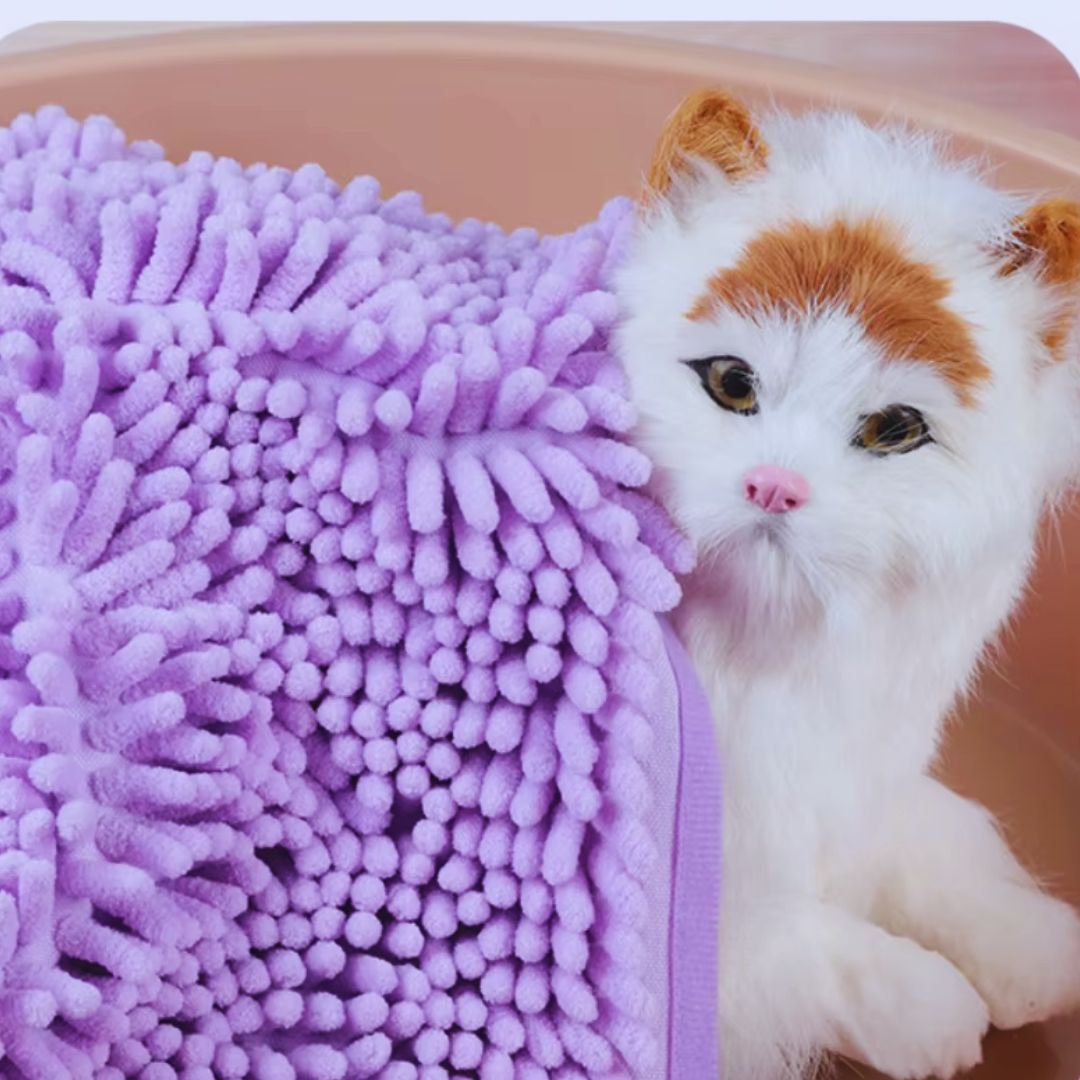 Close view of the lilac chenille loops and bound edge of the pet towel beside a white and ginger cat
