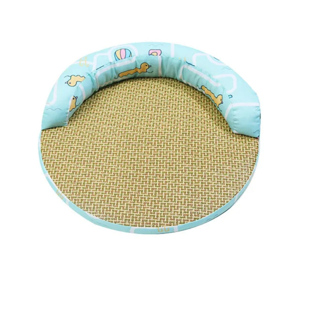 Round cat bed with a woven mat and an aqua padded rim printed with yellow ducks and beach balls