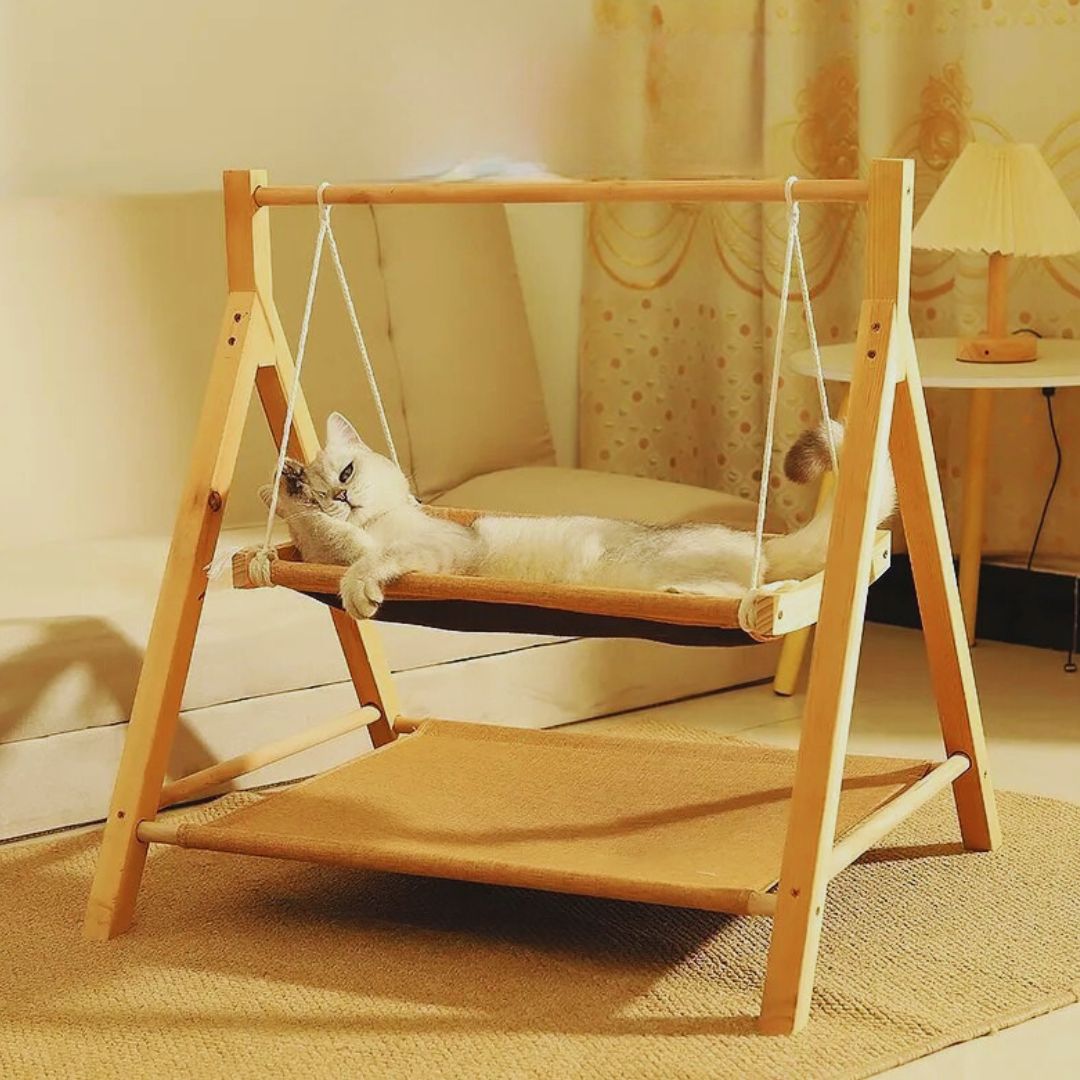 A white cat lying in the tan swing hammock of the wooden cat swing bed in a living room