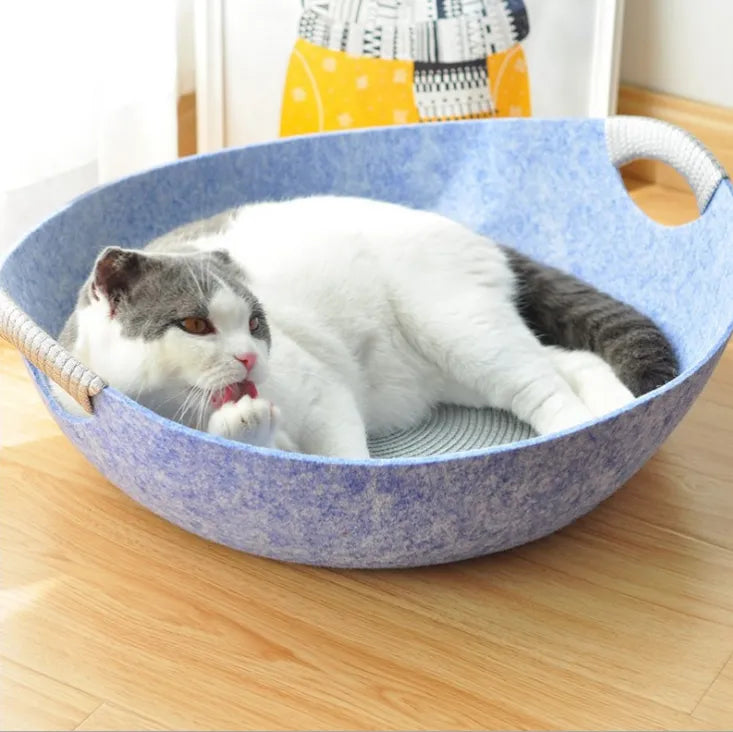 Grey and white cat lying in the blue felt cat bed basket, a rope-wrapped handle at each side