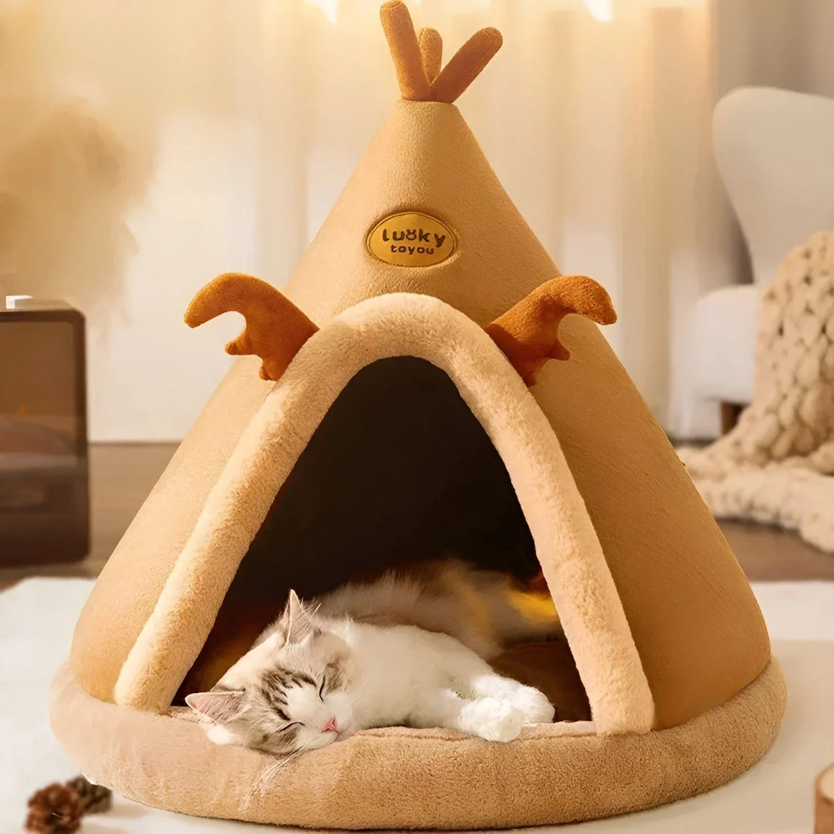 A white and grey cat asleep inside the caramel teepee cave bed