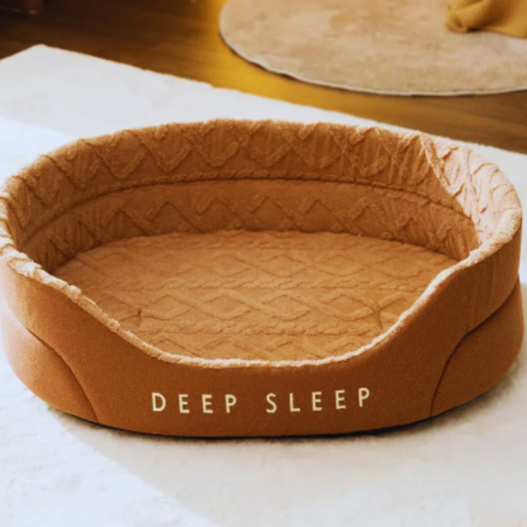 Caramel oval pet bed with raised sides, a lower front and a textured plush lining