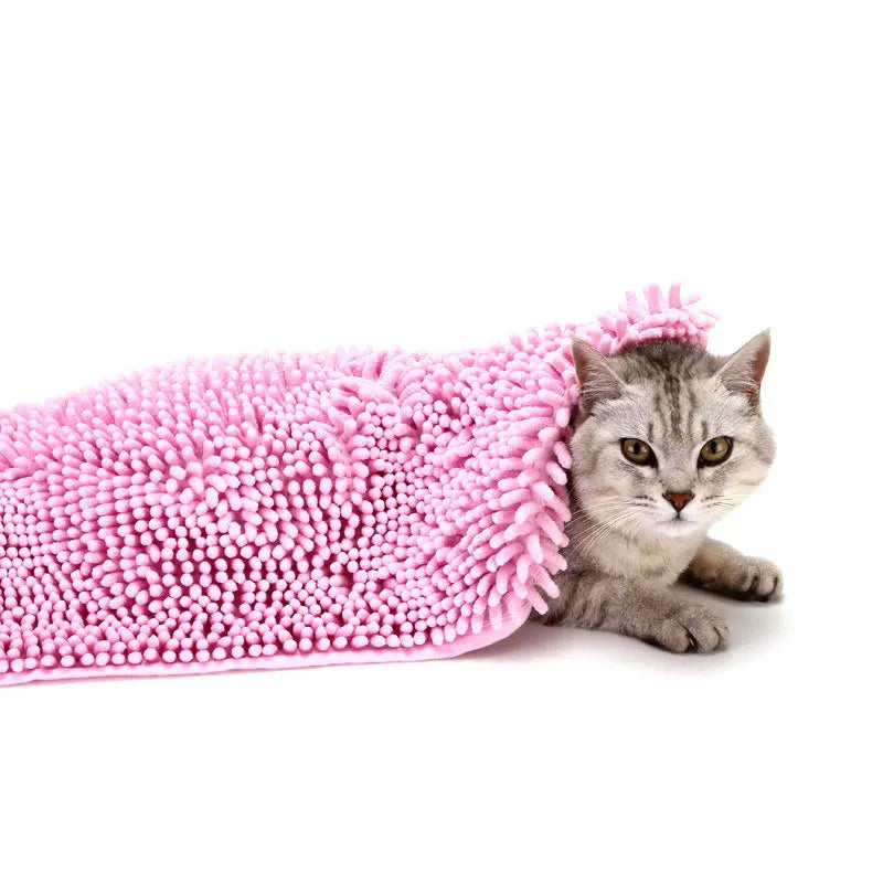 Pink chenille pet towel draped over a grey tabby cat lying on a white floor
