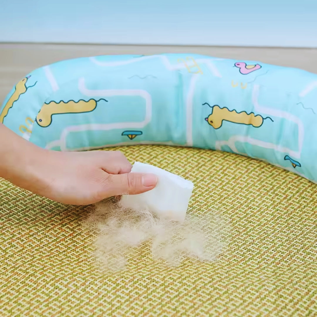 A hand wiping loose cat hair off the woven mat with a cloth