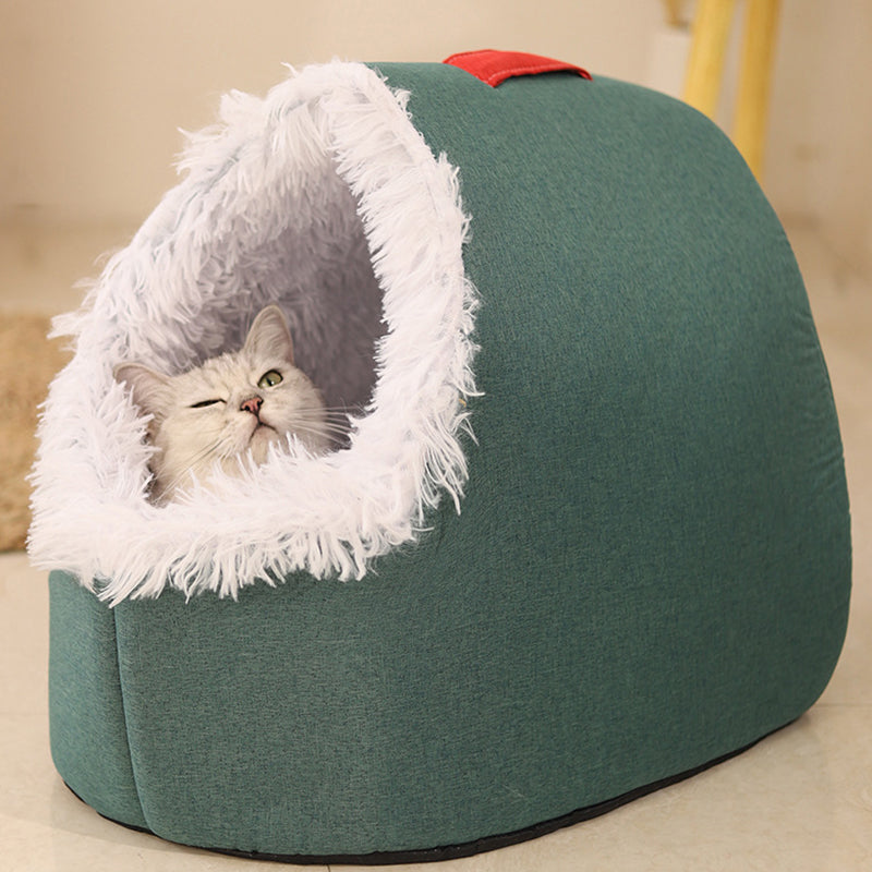A grey tabby cat looking out of the green cave bed with a white plush entrance