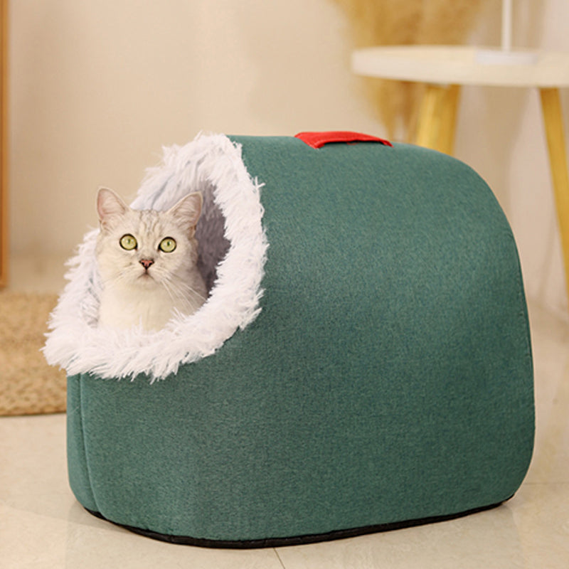 A silver cat sitting in the white plush entrance of the green cave bed
