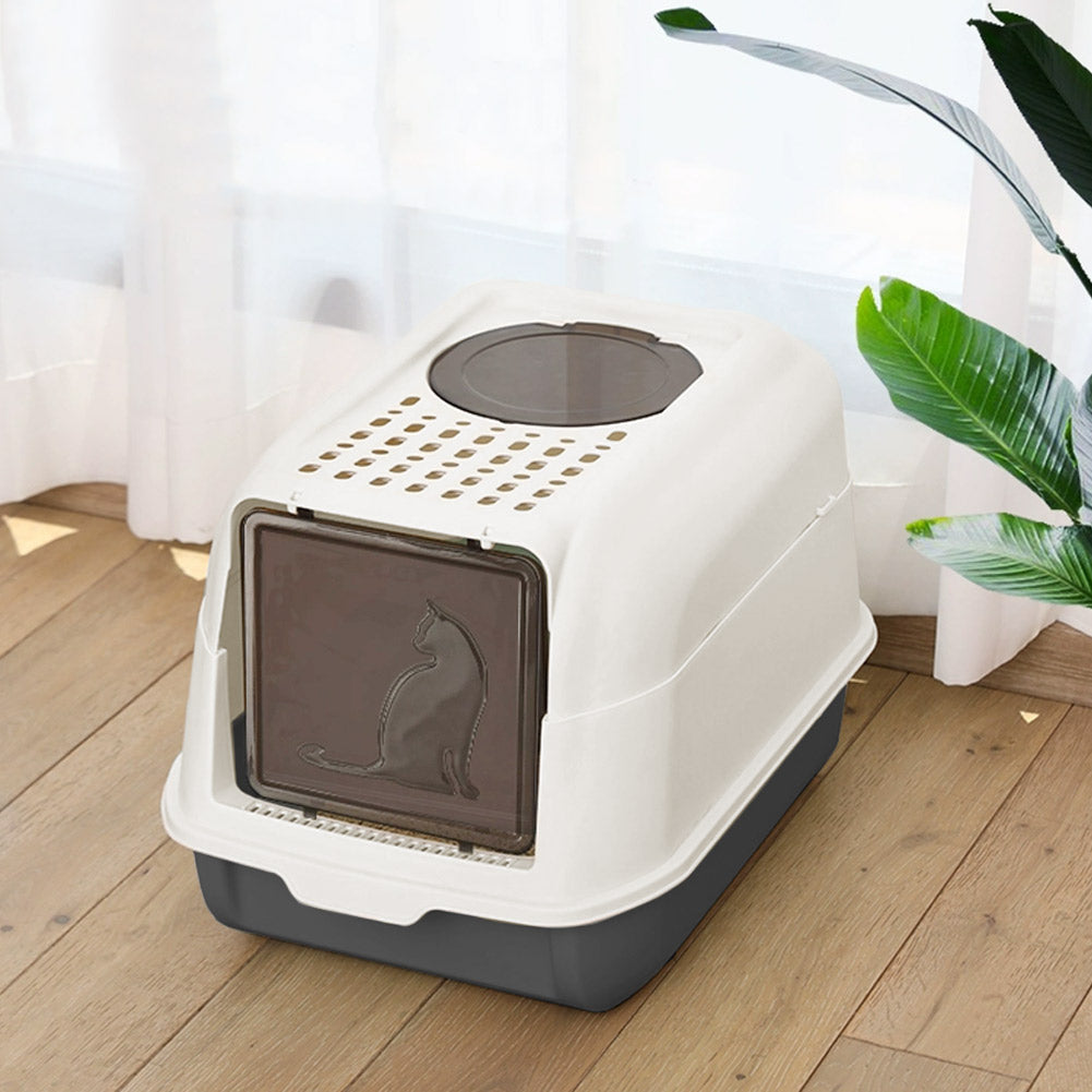 The cream and charcoal hooded litter box with its tinted front flap and round top lid, on a wooden floor