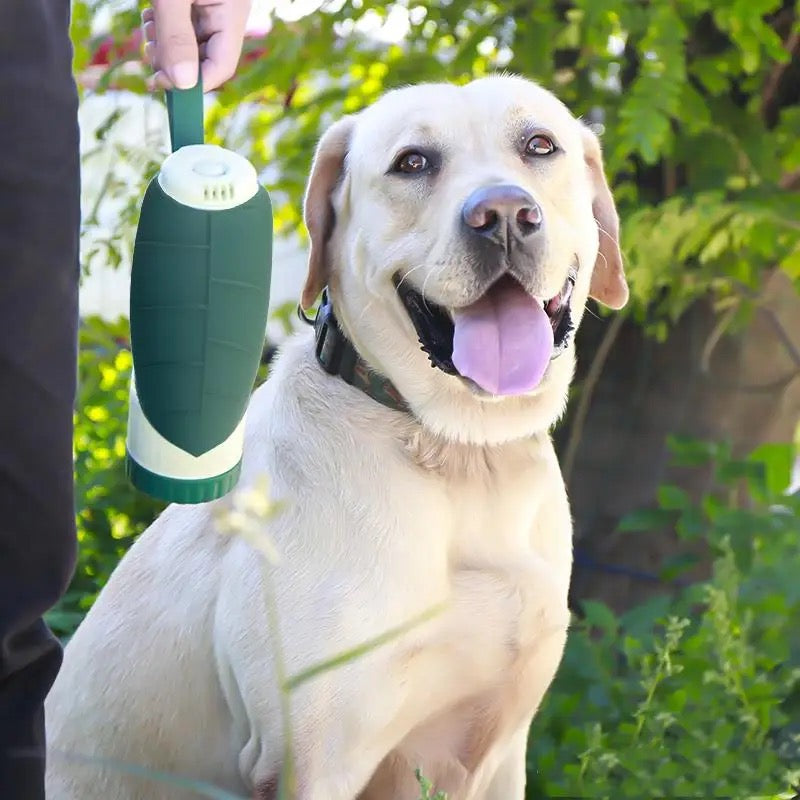 The green bottle hanging by its loop beside a smiling Labrador