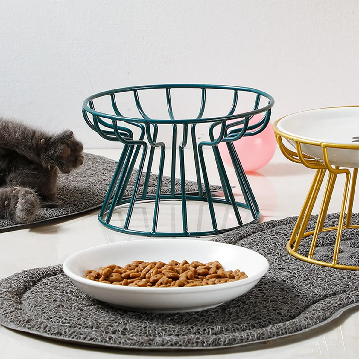 A ceramic bowl lifted out of its wire stand, beside a gold stand