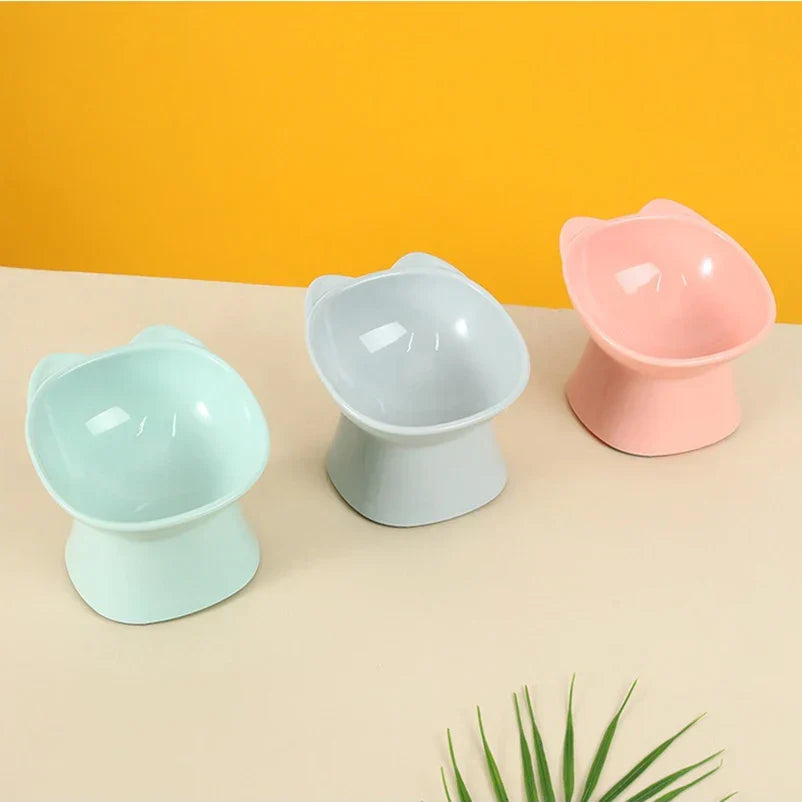 Three raised cat bowls on a yellow background, including a mint colour not sold here