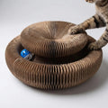 A tabby cat pawing the round accordion scratcher with a blue bell ball in its track