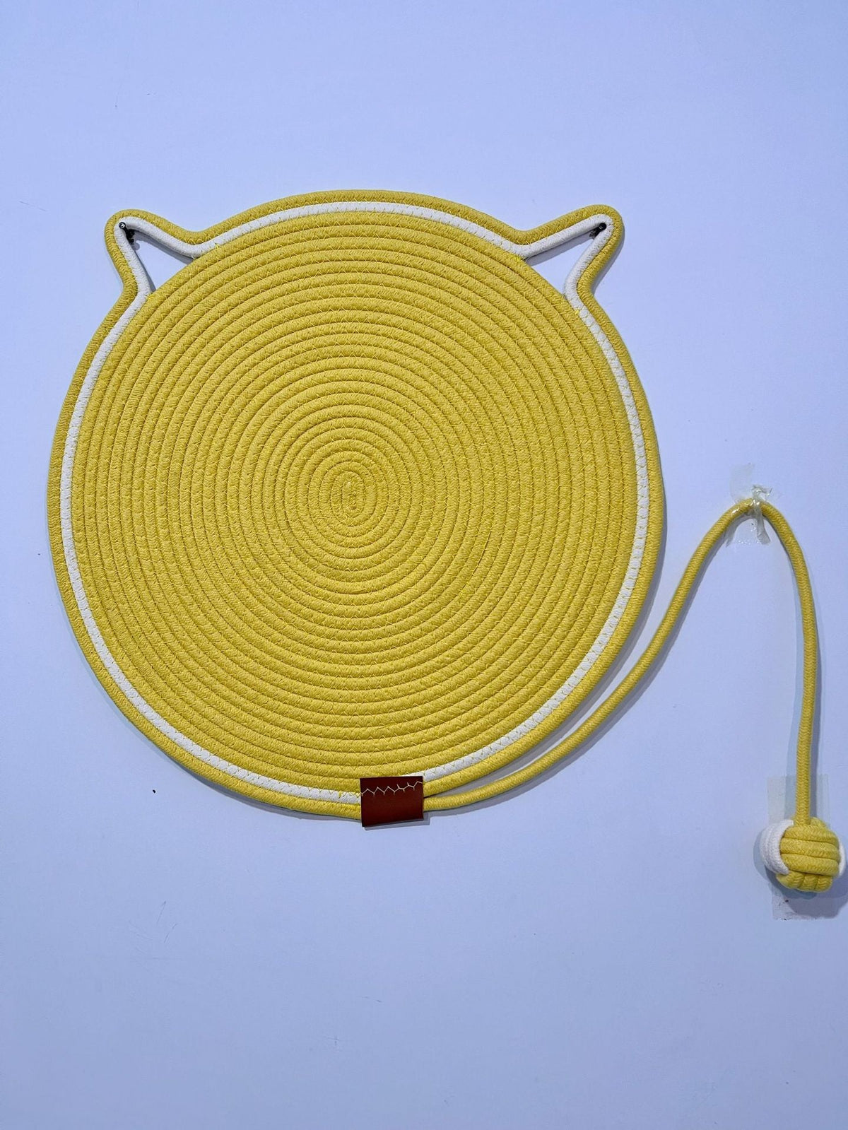 Yellow coiled rope scratching mat with a white edge and a rope ball toy