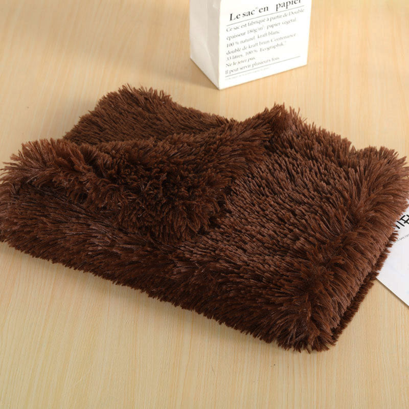 Dark brown long-pile plush dog blanket folded on a wooden table