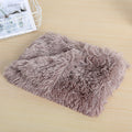Taupe long-pile plush dog blanket folded on a wooden table
