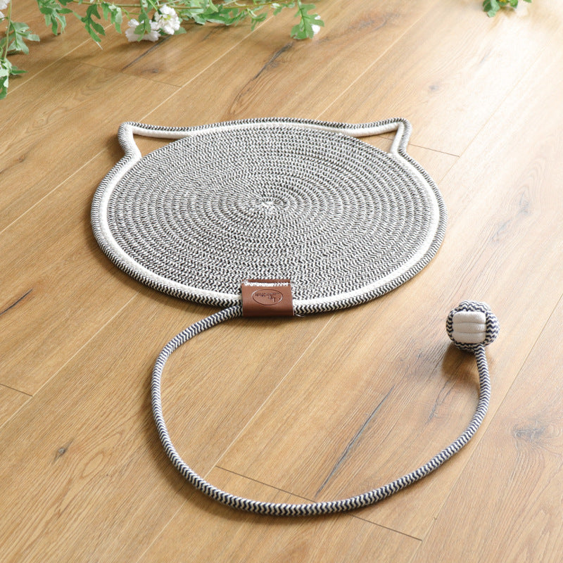 Grey coiled rope scratching mat with a white edge and a rope ball toy