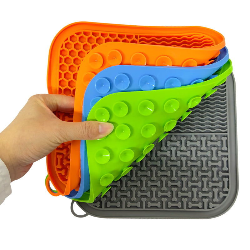 A hand holding a stack of lick mats, showing the suction cups underneath