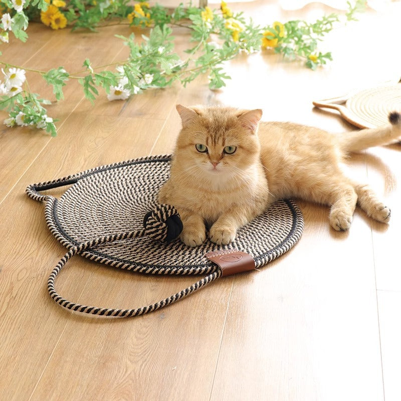 A ginger cat lying on the black and white rope scratching mat with its ball toy
