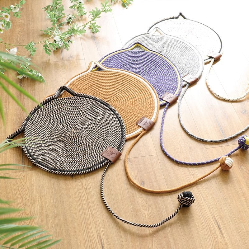 Rope scratching mats in black, caramel, purple, grey and white laid out in a row