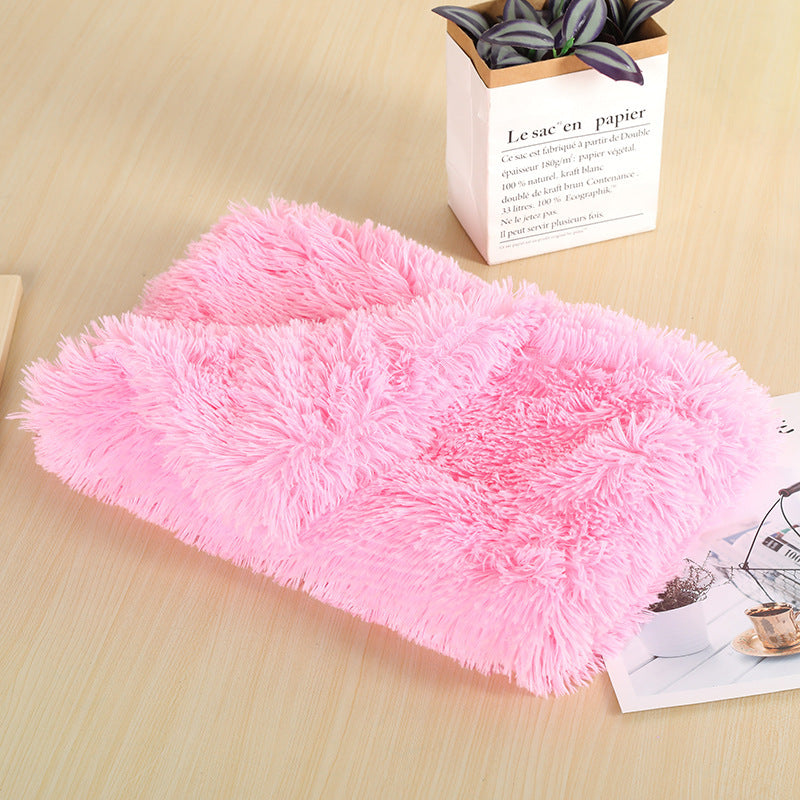 Pink long-pile plush blanket folded on a wooden table