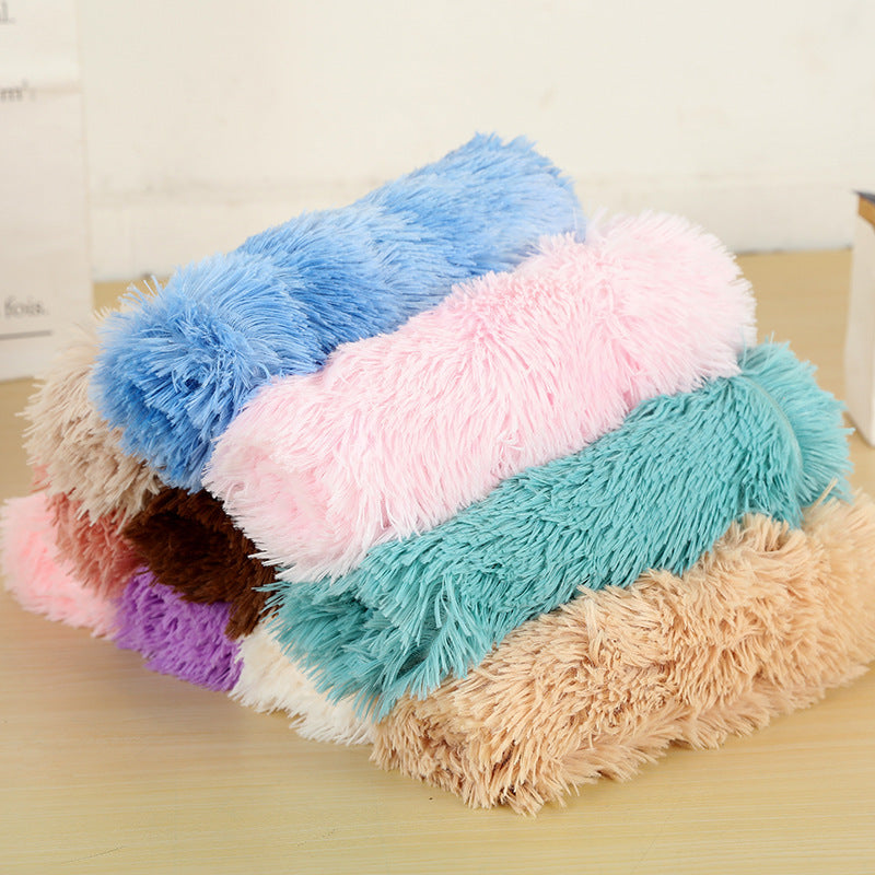A stack of rolled long-pile plush blankets in several colours