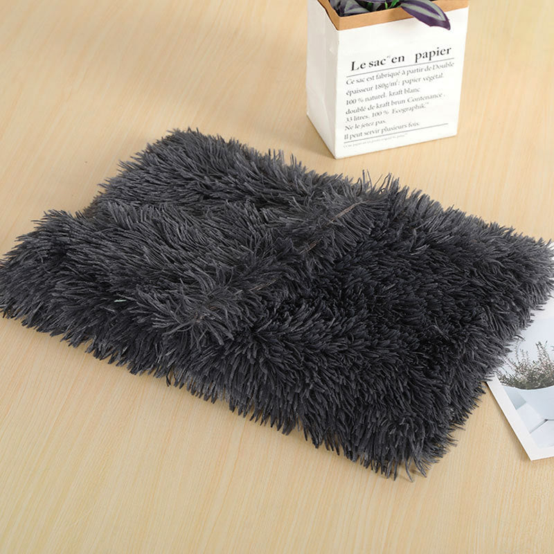 Dark grey long-pile plush dog blanket folded on a wooden table