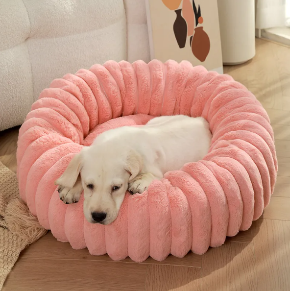 A pale puppy asleep in the coral pink ribbed plush donut bed