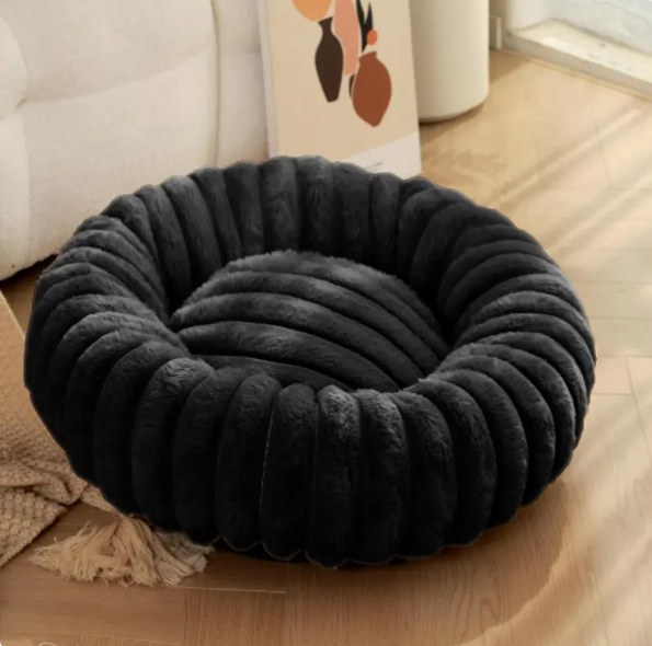 Black ribbed plush donut bed on a wooden floor