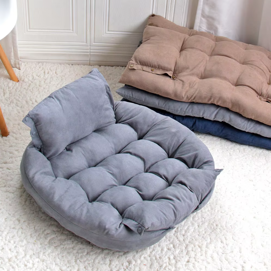 Grey convertible dog bed in its bed shape with the pillow backrest, taupe, grey and navy flat mats stacked behind