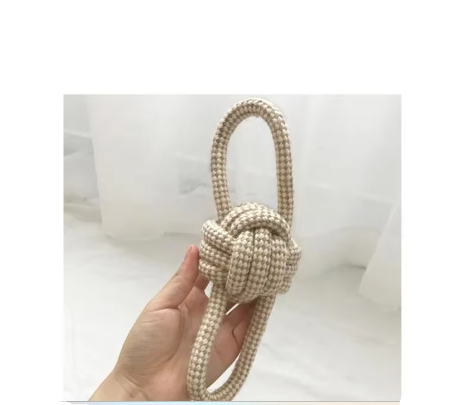 Cotton rope dog toy with a knotted ball and a loop on each side, held in one hand