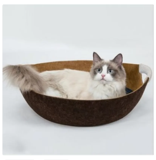 Ragdoll cat sitting in the brown felt cat bed basket with a tan inside
