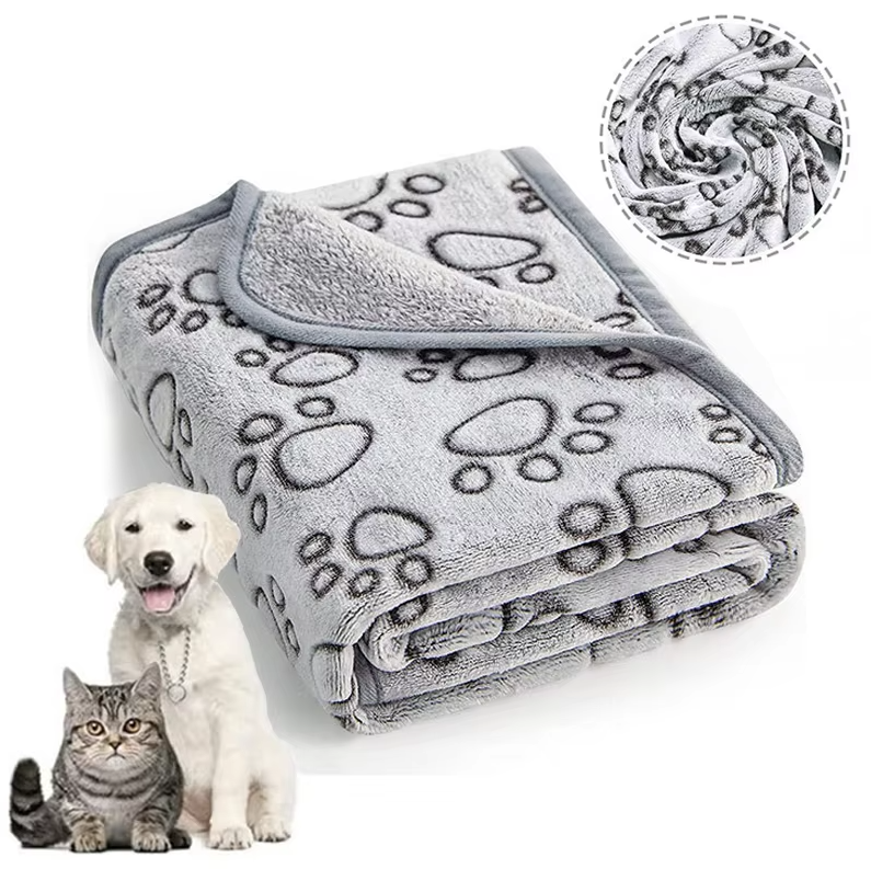 Folded grey paw print pet blanket with a grey bound edge, a white puppy and a tabby cat beside it