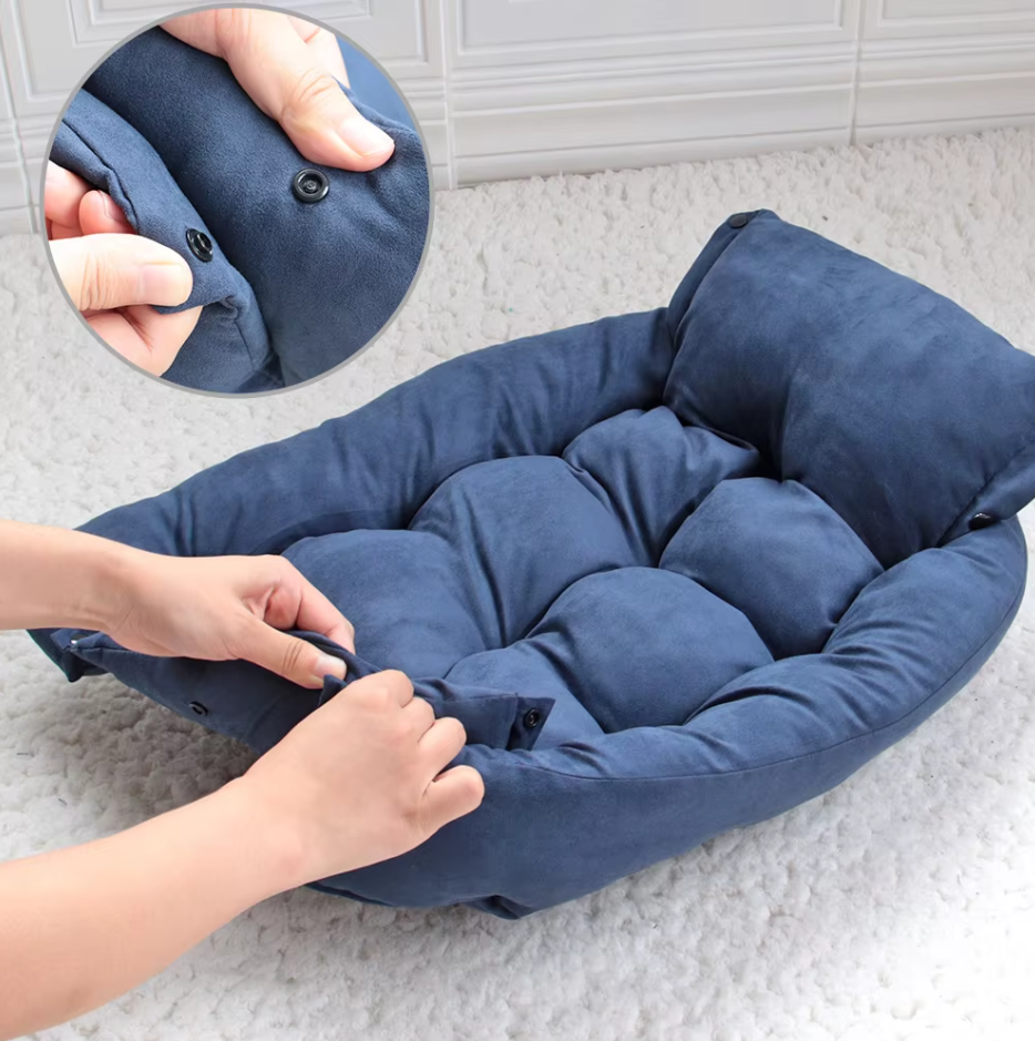 Hands snapping the navy convertible dog bed into its bed shape, with a close-up of a press stud
