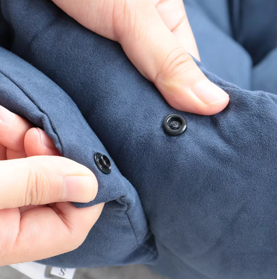 Close-up of hands fastening a press stud on the navy suede-look fabric