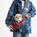 A small curly dog looking out of the red mesh pet sling worn across a person's body