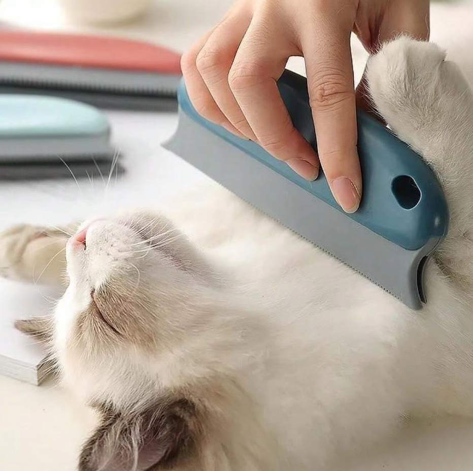A dark blue pet hair remover held against a white cat lying on its back